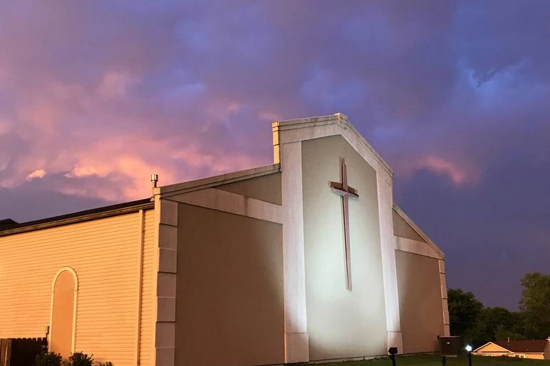 Southland Baptist Church’s illuminated facade and cross under a colorful sunset sky in Belton.